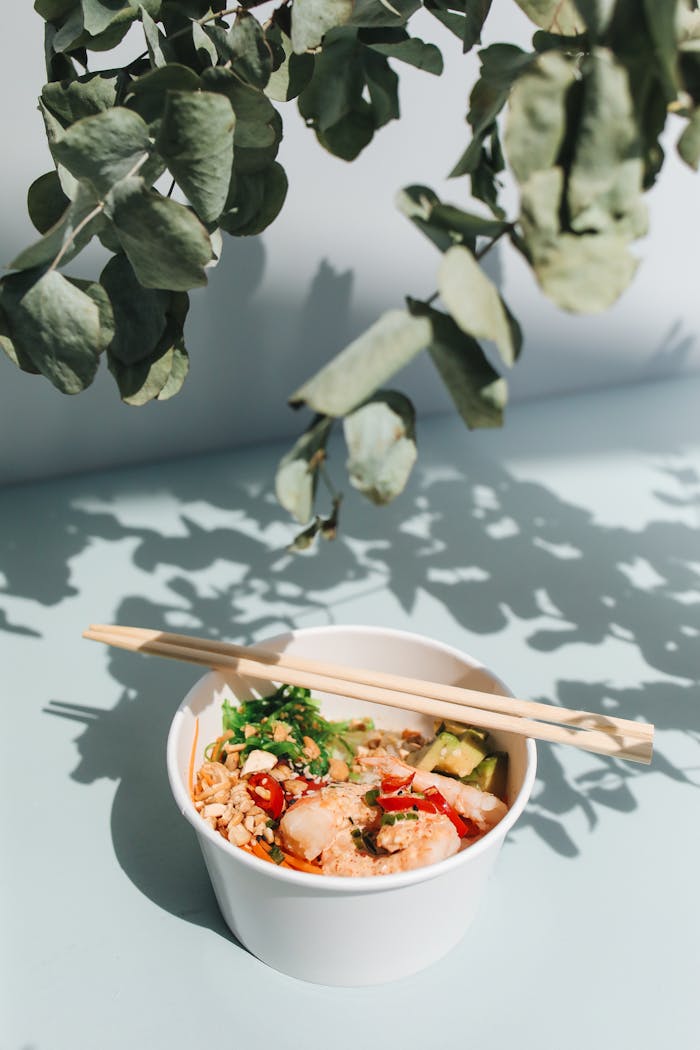 Bright and fresh Hawaiian poke bowl with chopsticks, garnished with avocado and greens. Perfect for food lovers.